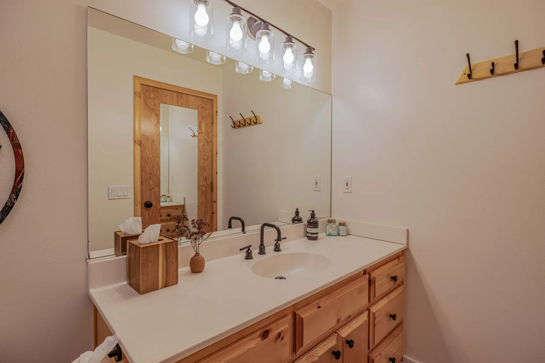 Primary en-suite bathroom vanity at Pine Grove Cabin with knotty pine cabinetry and dual faucets