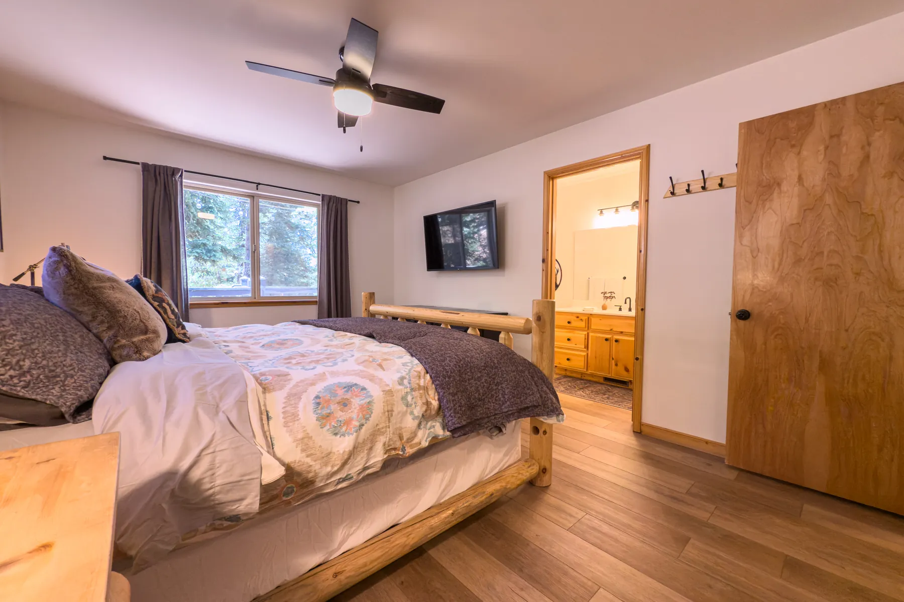 Primary bedroom at Pine Grove Cabin showing the king log bed, dresser, and en-suite doorway