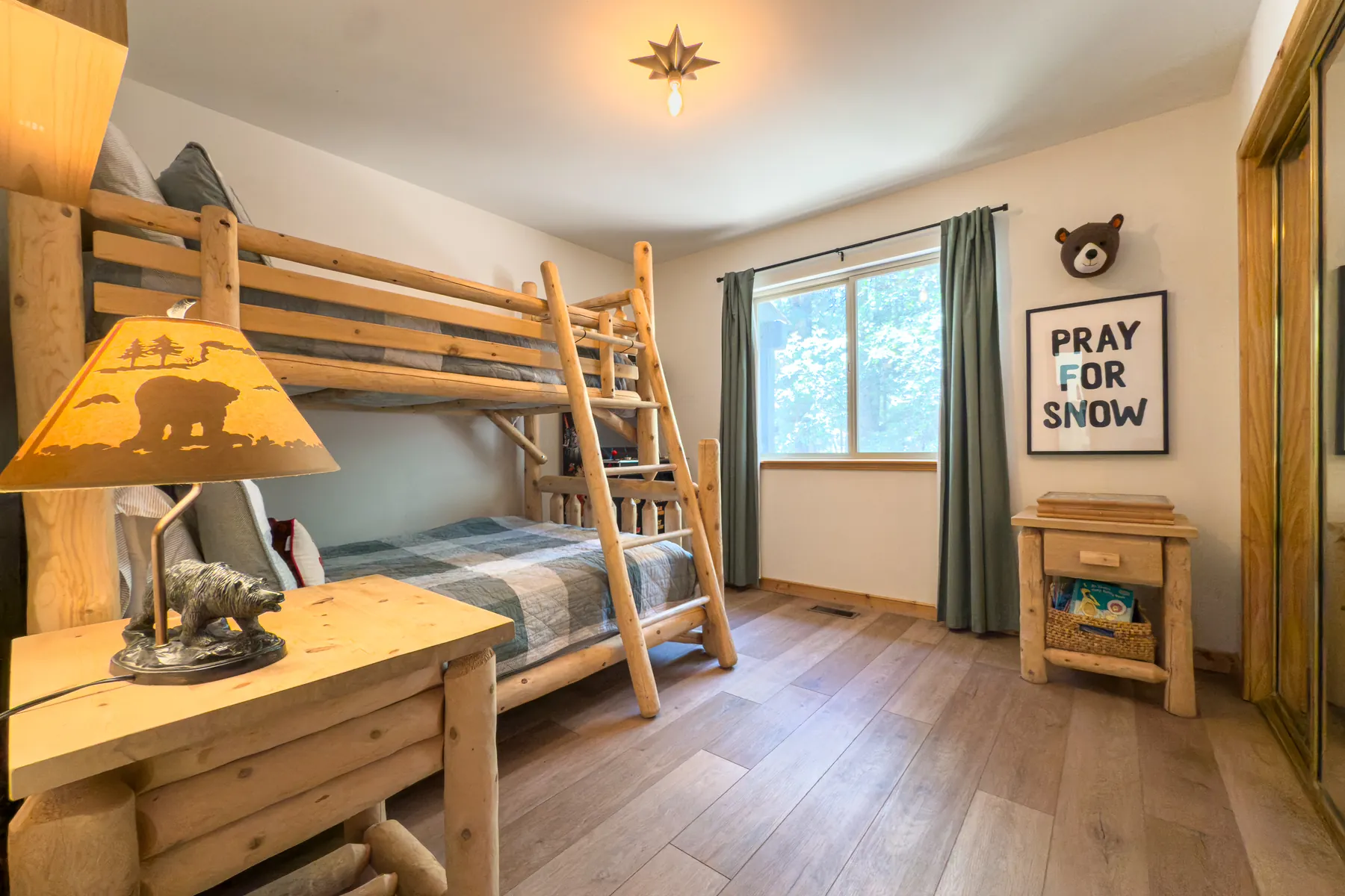 Bedroom Three at Pine Grove Cabin with a log bunk bed and Pray For Snow wall art