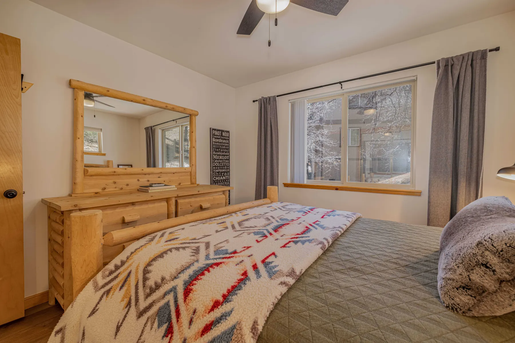 Bedroom Two at Pine Grove Cabin with a log dresser, mirror, and forest-facing window