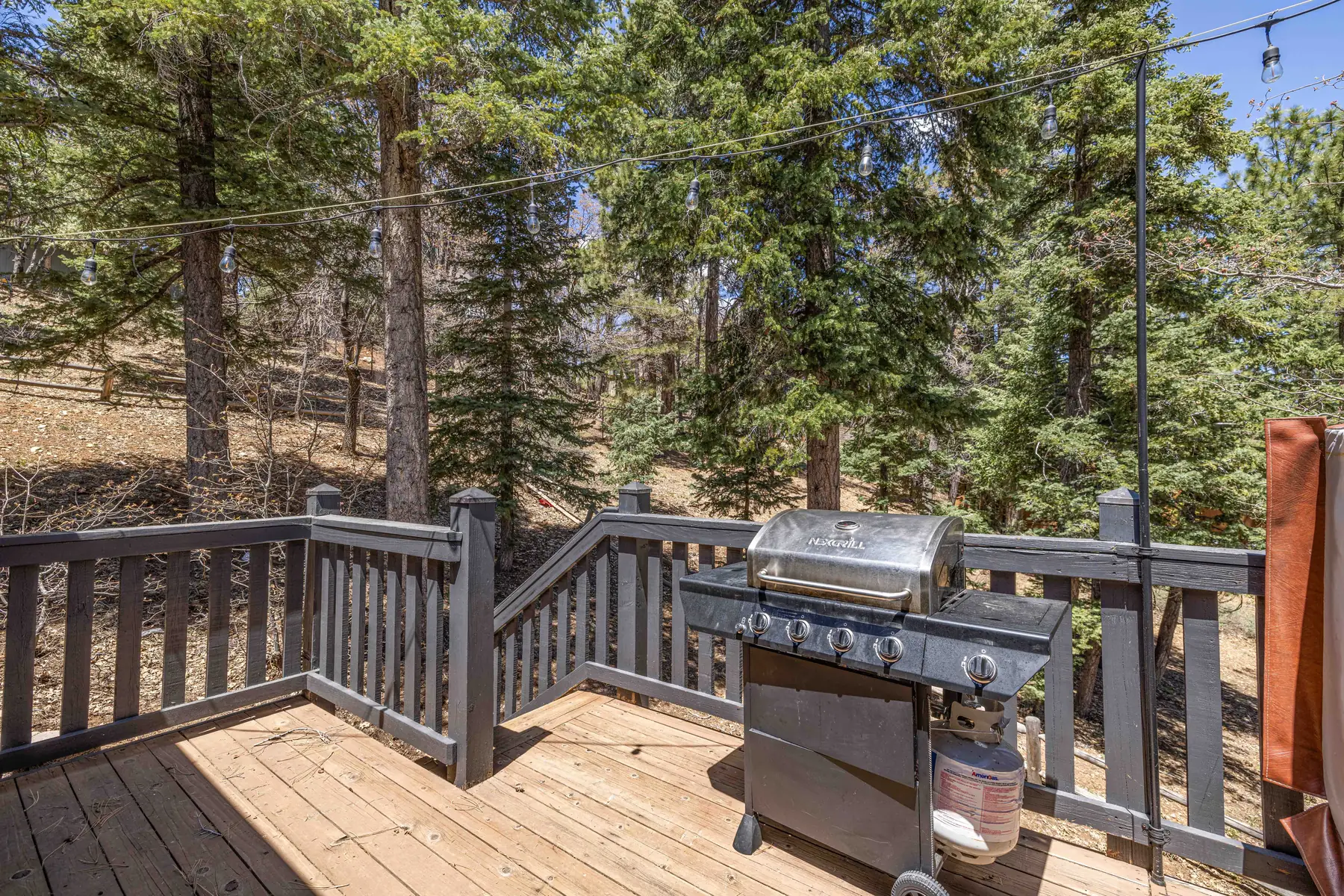Wraparound deck at Pine Grove Cabin with Adirondack chairs and a dining table set for outdoor meals