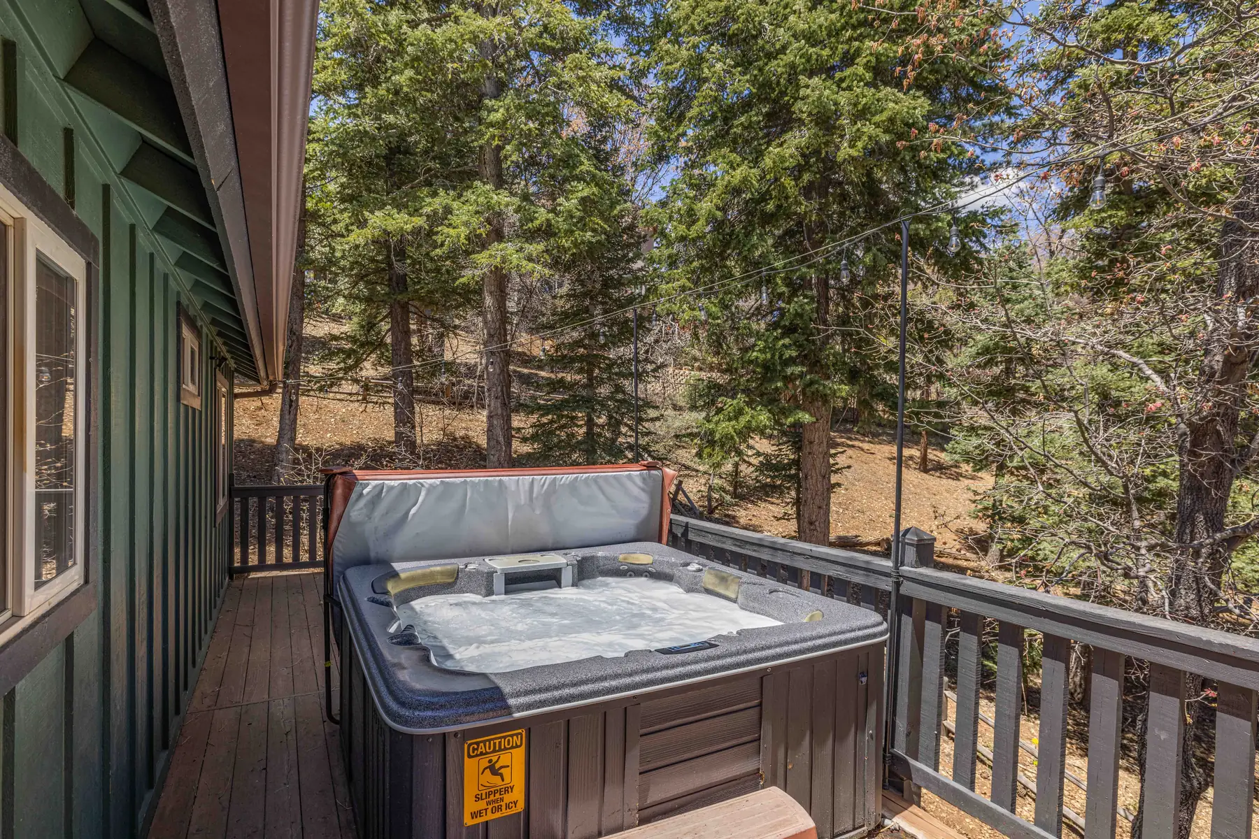 Wide view of the wraparound deck at Pine Grove Cabin looking out toward the forest and neighboring cabins