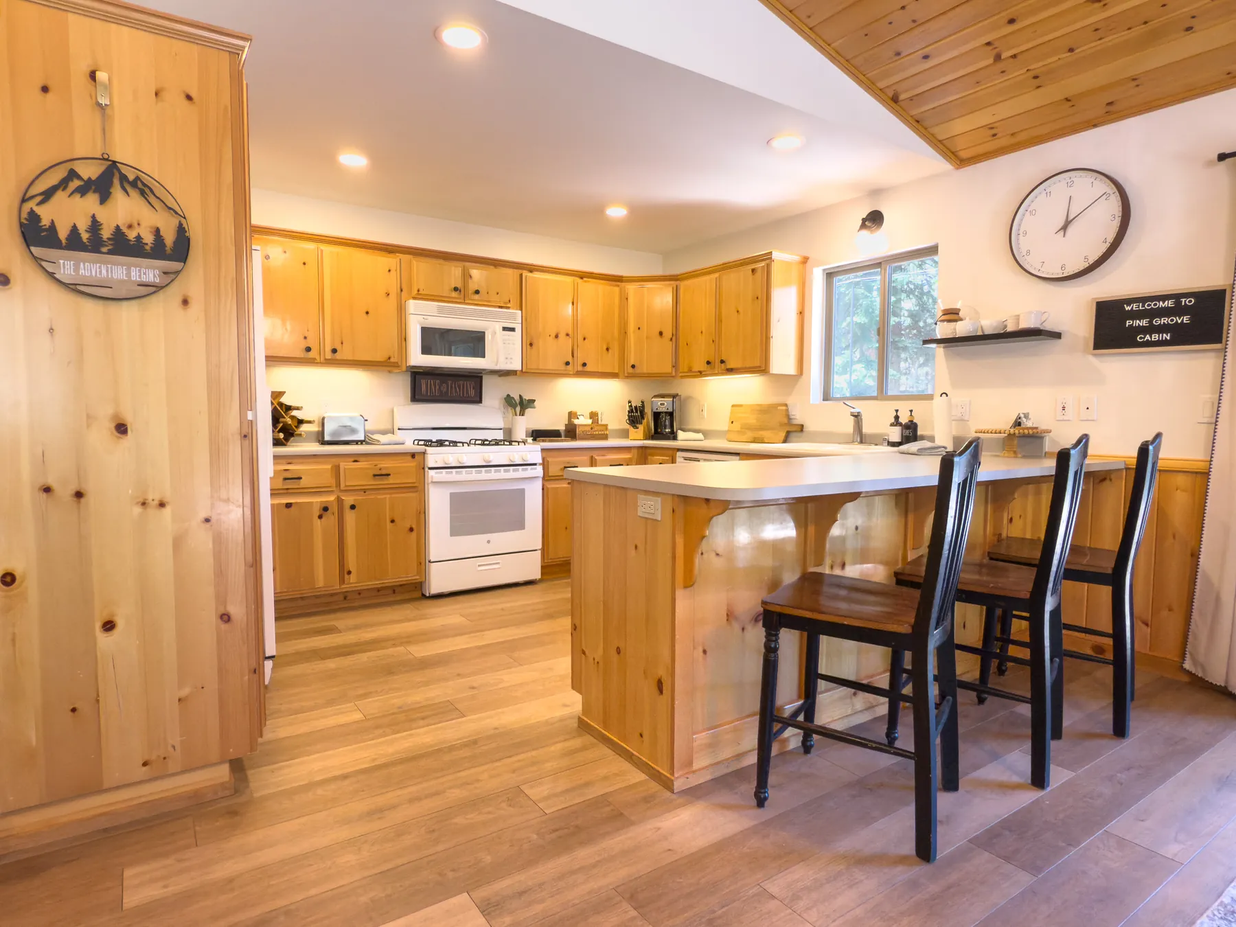 Kitchen at Pine Grove Cabin with knotty pine cabinetry, white refrigerator, and gas range